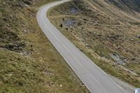 a motorcycle parked on a small mountain side road near mountains with no cars driving on it