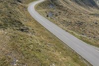 a motorcycle parked on a small mountain side road near mountains with no cars driving on it