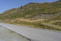 a motorcycle parked on a small mountain side road near mountains with no cars driving on it