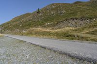 a motorcycle parked on a small mountain side road near mountains with no cars driving on it