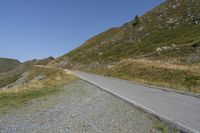 a motorcycle parked on a small mountain side road near mountains with no cars driving on it