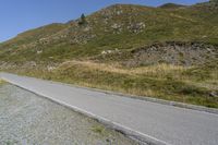 a motorcycle parked on a small mountain side road near mountains with no cars driving on it