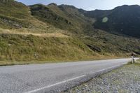 a person riding a skateboard down a steep hill next to a dirt road with mountains