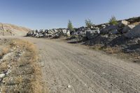 there is a bike rider on a paved dirt road through rocky area near a mountain