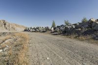 there is a bike rider on a paved dirt road through rocky area near a mountain