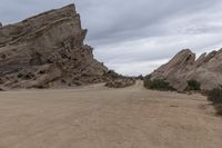 the road is made up of large mountains and sand dunes with two motorcycles parked in front