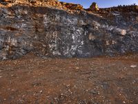 large rocks and dirt covered hills on a sunny day with a sky background and a person walking away