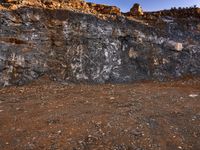 large rocks and dirt covered hills on a sunny day with a sky background and a person walking away