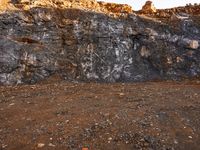 large rocks and dirt covered hills on a sunny day with a sky background and a person walking away