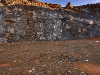 large rocks and dirt covered hills on a sunny day with a sky background and a person walking away