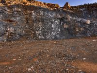 large rocks and dirt covered hills on a sunny day with a sky background and a person walking away