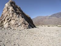 a pile of rocks on the side of a hill in an arid area with mountains