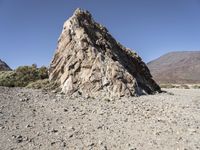 a pile of rocks on the side of a hill in an arid area with mountains