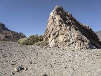 a pile of rocks on the side of a hill in an arid area with mountains