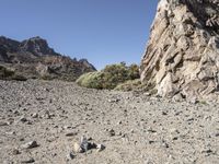 a pile of rocks on the side of a hill in an arid area with mountains