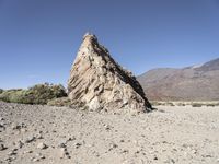 a pile of rocks on the side of a hill in an arid area with mountains