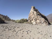 a pile of rocks on the side of a hill in an arid area with mountains