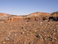 an empty dirt field in the middle of nowhere surrounded by hills and rocks in the background