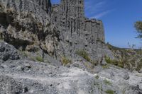 some very large rocky formations with rocks in the back ground and trees and grass on both sides