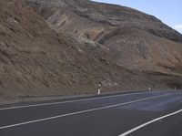 a car sitting on the side of the road with a mountain in the background and a yellow traffic light