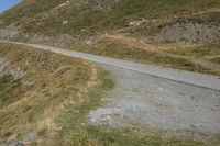 a motorcycle parked on a small mountain side road near mountains with no cars driving on it