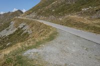 a motorcycle parked on a small mountain side road near mountains with no cars driving on it