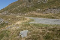 a motorcycle parked on a small mountain side road near mountains with no cars driving on it