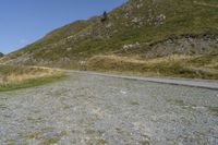 a curve road stretches into the distance on the hillside top next to a grassy hillside