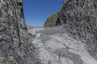 a large cliff face with a person standing on top of it and a mountaintop near the side of it