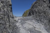 a large cliff face with a person standing on top of it and a mountaintop near the side of it