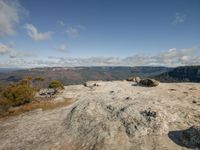 there are clouds on the blue sky above the rocky valley as a rock formation sits on top