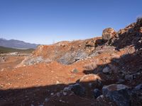 a barren area with a few rocks and dirt on it's side and a large mountain in the distance