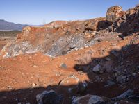 a barren area with a few rocks and dirt on it's side and a large mountain in the distance