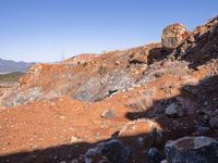 a barren area with a few rocks and dirt on it's side and a large mountain in the distance