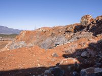 a barren area with a few rocks and dirt on it's side and a large mountain in the distance