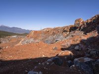 a barren area with a few rocks and dirt on it's side and a large mountain in the distance