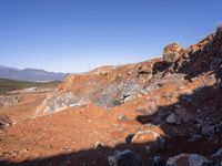 a barren area with a few rocks and dirt on it's side and a large mountain in the distance