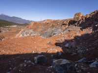 a barren area with a few rocks and dirt on it's side and a large mountain in the distance