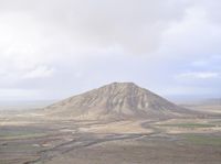 a mountainous landscape with hills in the background as seen from atop a hill top with a view of a small valley