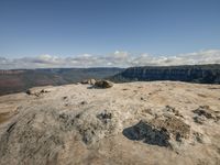 a couple of rocks sitting on top of a mountain with a view of a valley in the distance