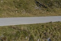 a motorcycle parked on a small mountain side road near mountains with no cars driving on it