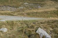 a motorcycle parked on a small mountain side road near mountains with no cars driving on it