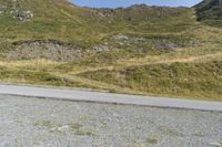 a motorcycle parked on a small mountain side road near mountains with no cars driving on it