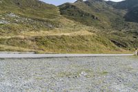 a motorcycle parked on a small mountain side road near mountains with no cars driving on it