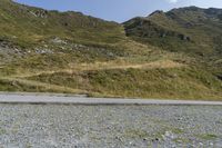 a motorcycle parked on a small mountain side road near mountains with no cars driving on it