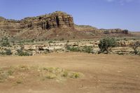 an outback car parked at a corner of a desert road with steep cliffs in the background