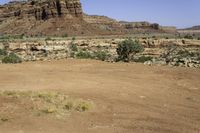 an outback car parked at a corner of a desert road with steep cliffs in the background