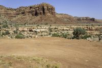 an outback car parked at a corner of a desert road with steep cliffs in the background