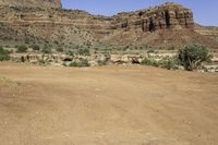 an outback car parked at a corner of a desert road with steep cliffs in the background