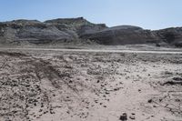 a barren and muddy landscape with rocks, rocks, dirt, dirt and grass on the ground